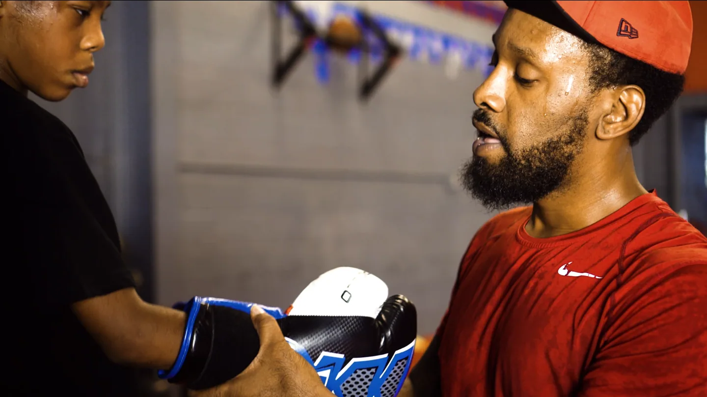Mike Starr helping a young boxer put on gloves